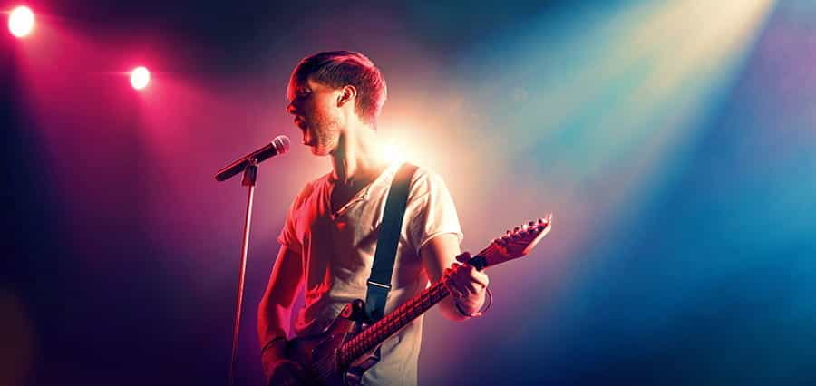 A man singing into a microphone while playing the guitar.