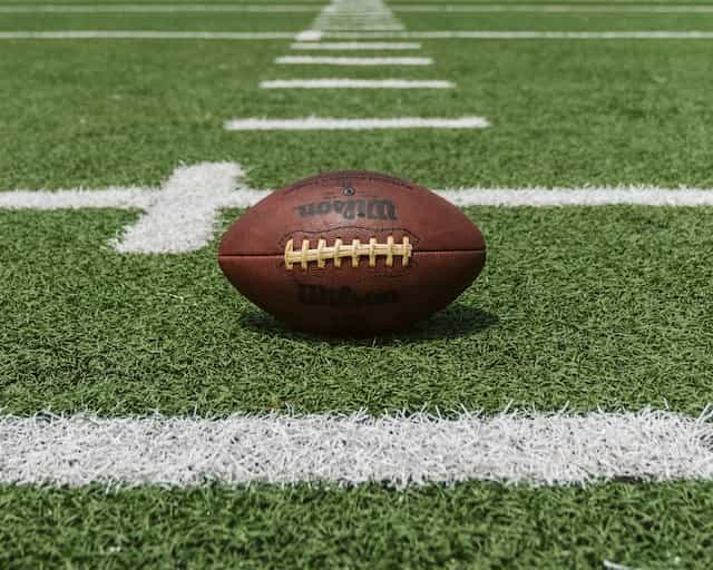 A classic American football sitting on an outdoor football pitch at the start of a game.